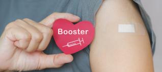 Person holding up "booster" sticker with bandaide on arm